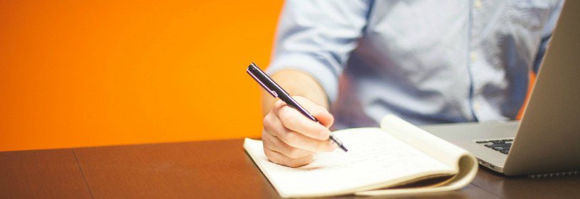 Man at laptop with notepad and pen