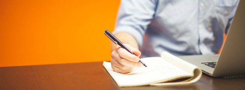 Man at laptop with notepad and pen