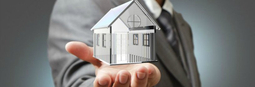 Business man holding glass house