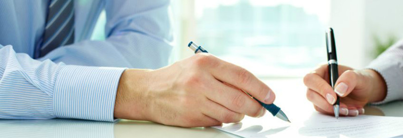 Man and woman signing document with pens