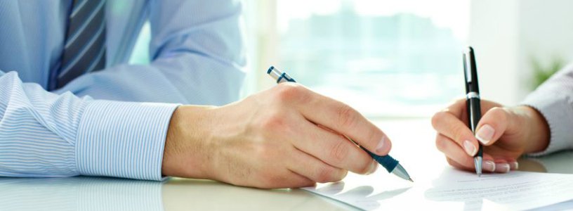 Man and woman signing document with pens