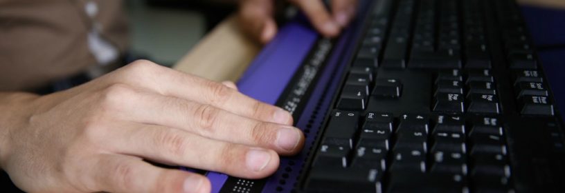 Man using braille adapter attached to keyboard