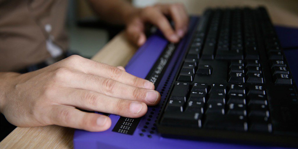 Man using braille adapter attached to keyboard