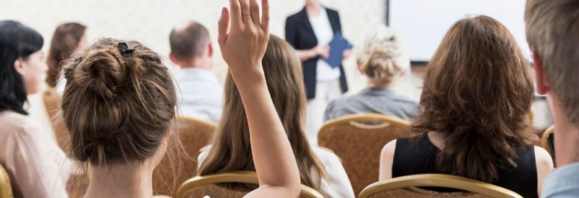 Woman with hand raised asking question