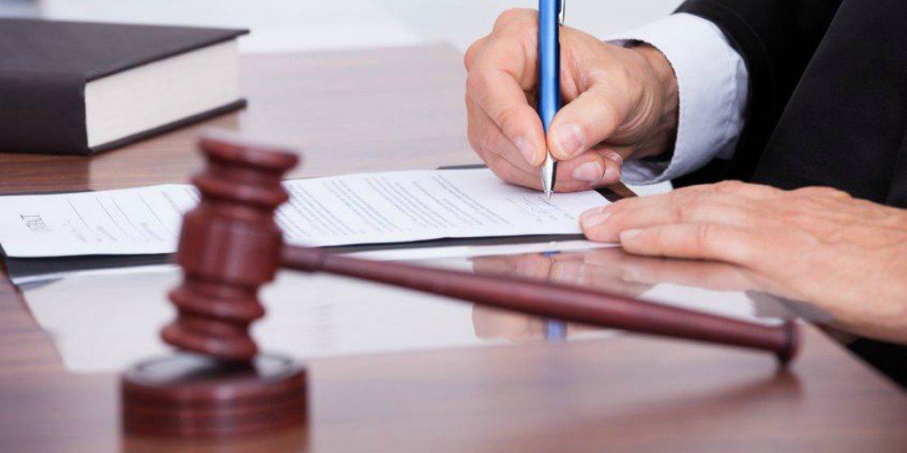 Gavel and judge using pen to sign a document