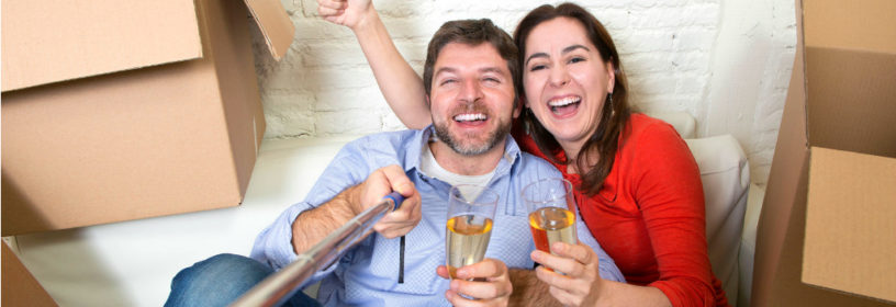 young couple drinking champagne with boxes in house