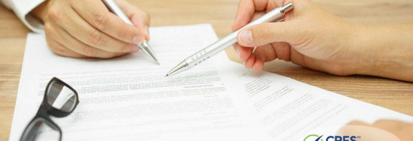 paperwork on a desk with two people pointing at it with pens
