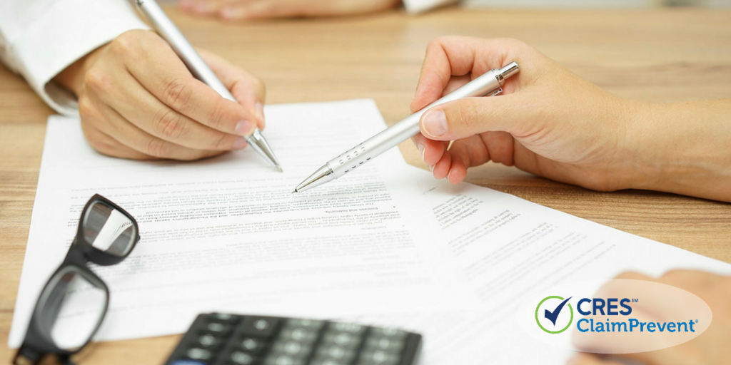 paperwork on a desk with two people pointing at it with pens