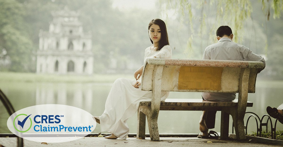 Husband and wife sitting on opposite sides of a bench facing away from each other