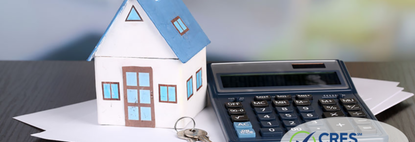 House figurine on documents next to calculator