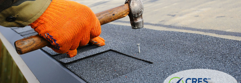 hand hammering nail into roof shingle