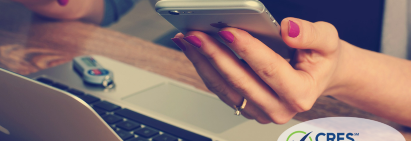 woman at desk holding smart phone
