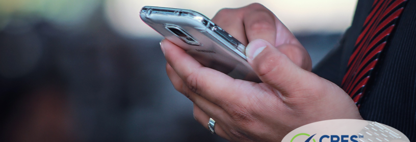 Close up of man in black dress shirt with red striped tie tapping cell phone screen with his finger