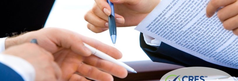 2 sets of male hands looking at legal documents with pen in hand