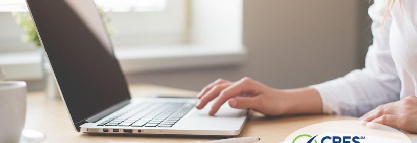 female at laptop using mouse pad with notebook next to her