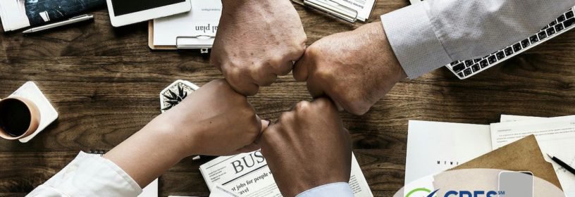 4 team members bumping fists in a group over an office table