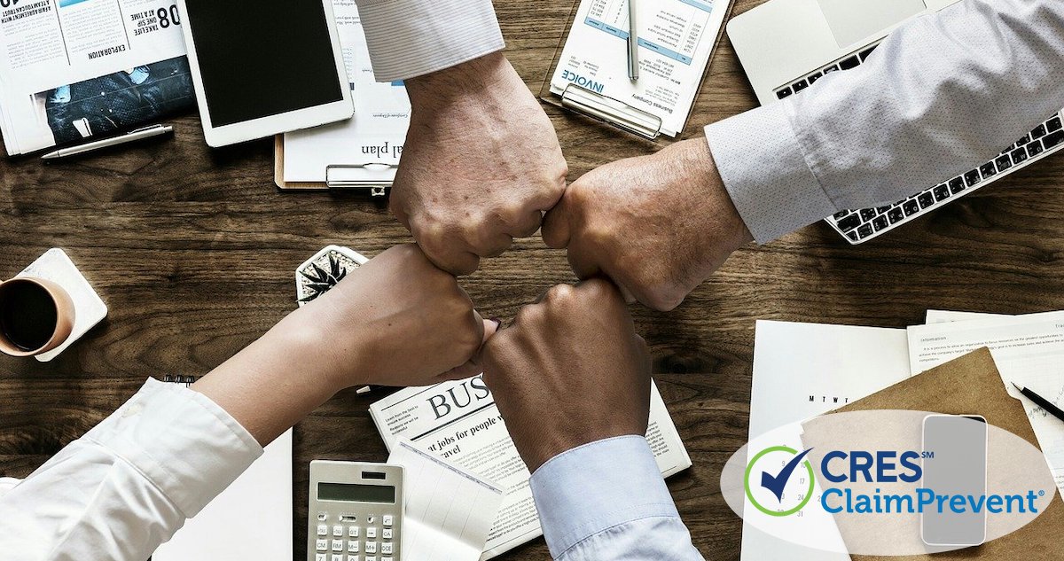 4 team members bumping fists in a group over an office table