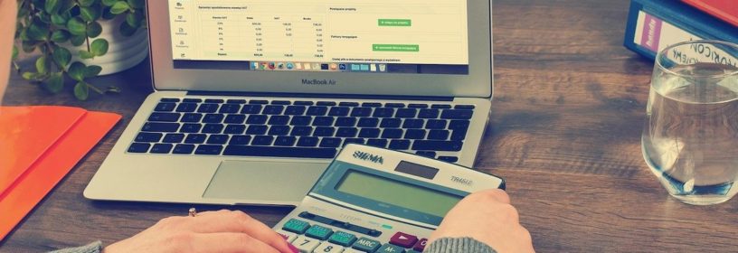 woman using calculator in front of computer with spreadsheet