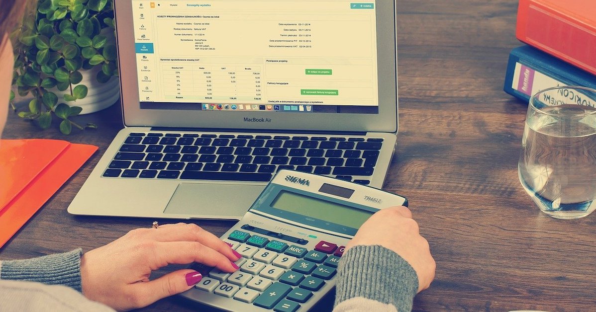 woman using calculator in front of computer with spreadsheet