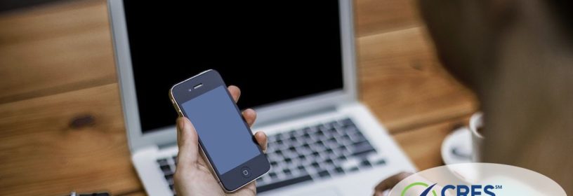man at laptop holding smartphone