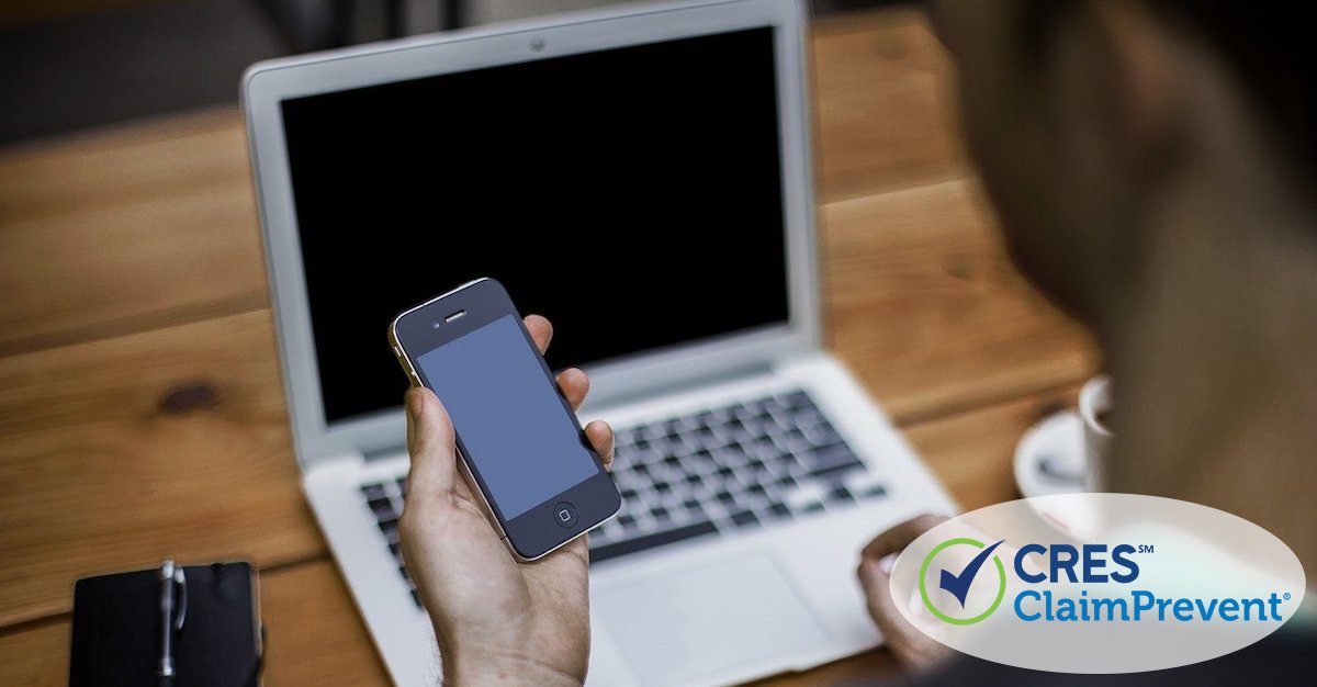 man at laptop holding smartphone