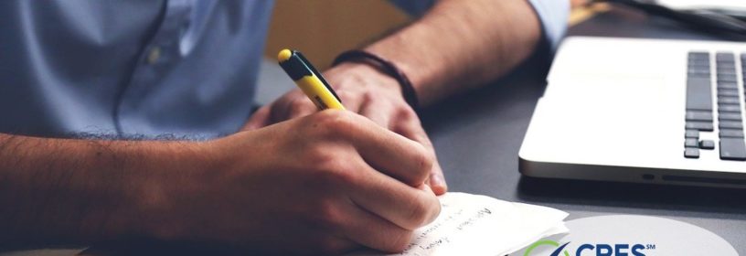 man taking notes in front of laptop