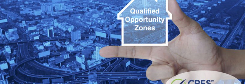 hand holding house concept image with qualified opportunity zones text overlaid on a cityscape