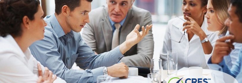 Five business professionals sitting around conference table having a discussion