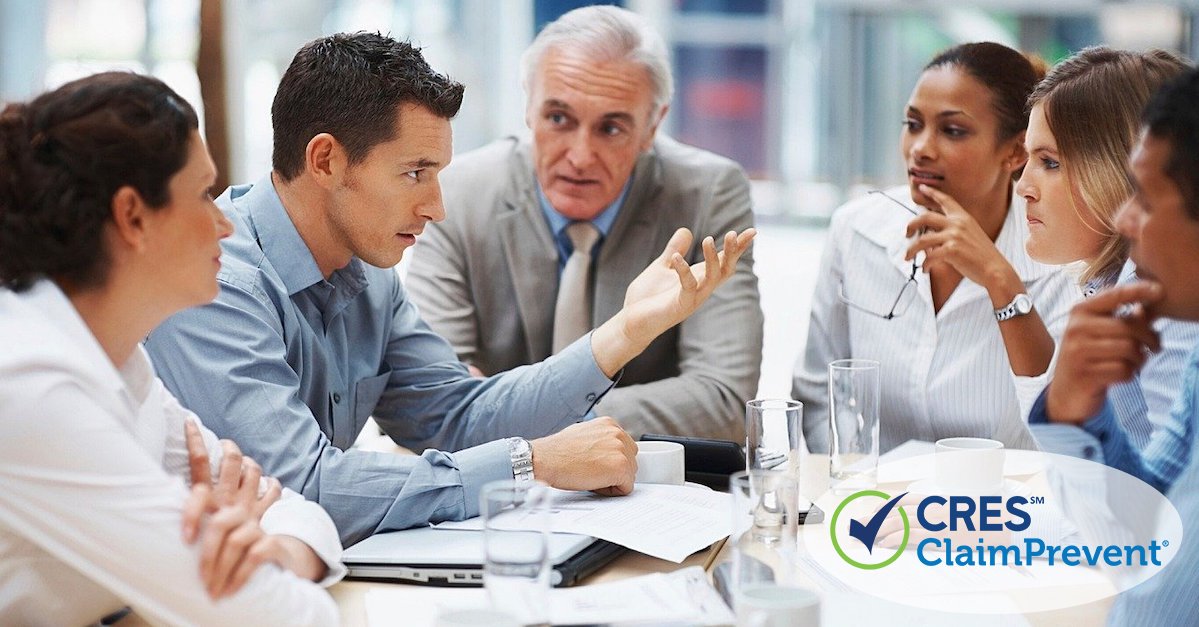 Five business professionals sitting around conference table having a discussion