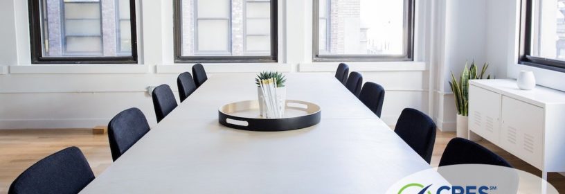 rectangular table in office space with empty chair surrounding it