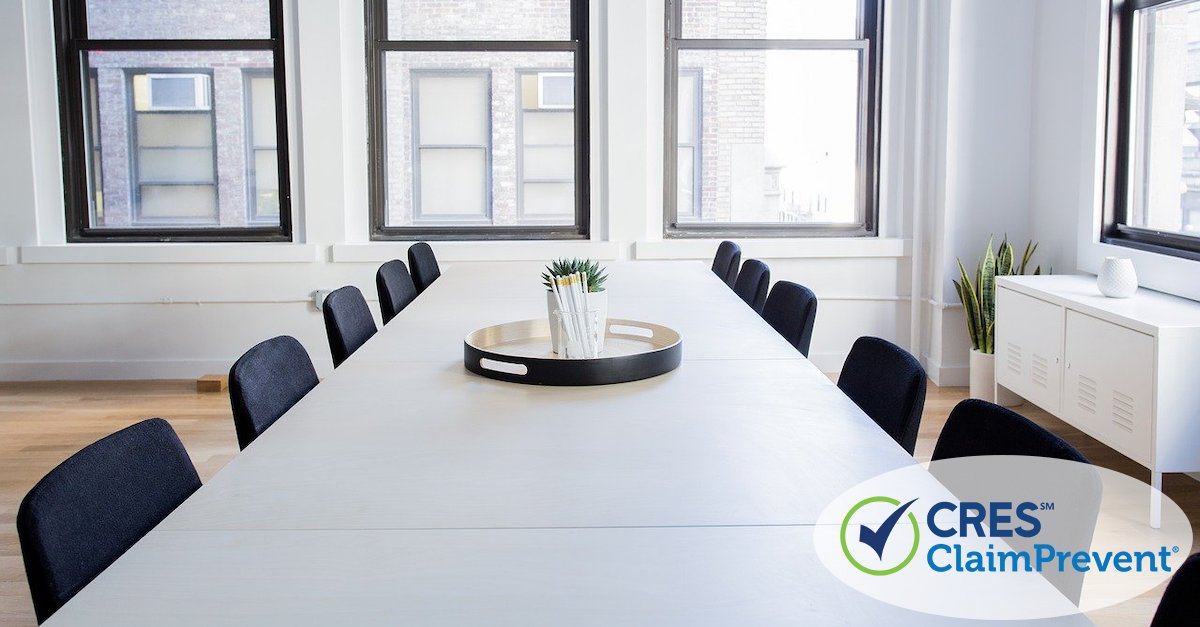 rectangular table in office space with empty chair surrounding it