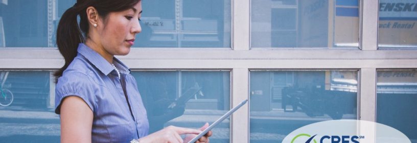 woman standing outside in front of building on ipad
