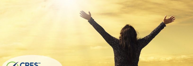 woman holding hands up towards sunrise