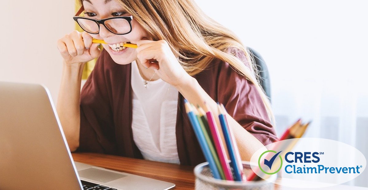 woman looking at laptop screen frustrated with pencil in her mouth