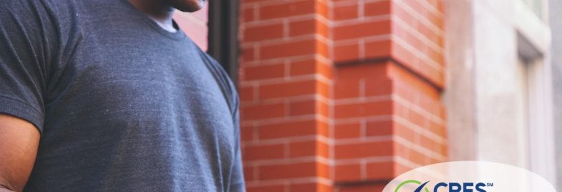 male outside brick building texting on cell phone