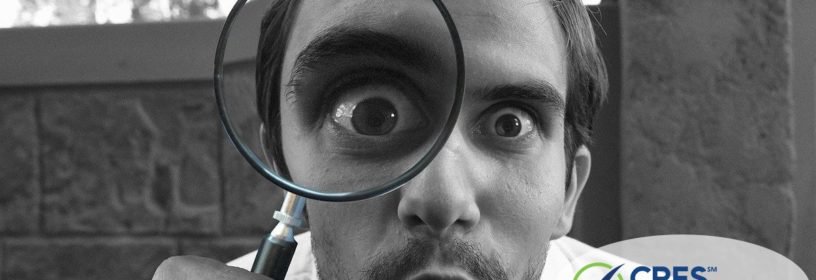 man looking into magnifying glass