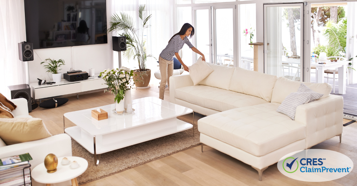 woman in living room by couch fluffing pillow