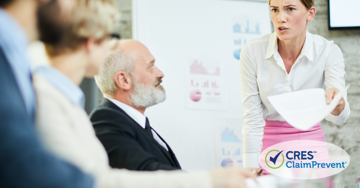 man with beard sitting women with paper standing